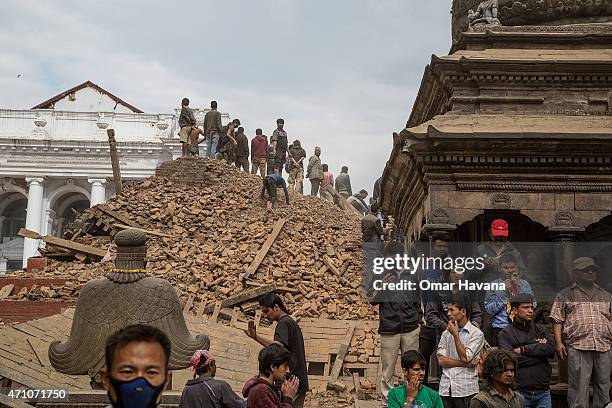 Emergency workers and bystanders clear debris while searching for survivors under a collapsed temple in Basantapur Durbar Square following an...