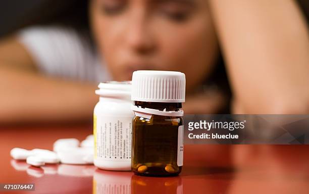 pill bottles with pills next to them and a woman in back - verslaving stockfoto's en -beelden