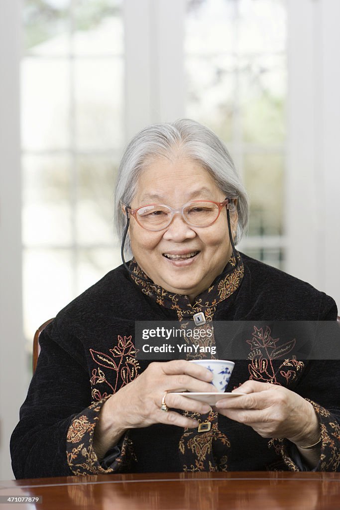 Ältere asiatische Frau trinken Tee, chinesische ehemaliger Großmutter wie zu Hause fühlen.