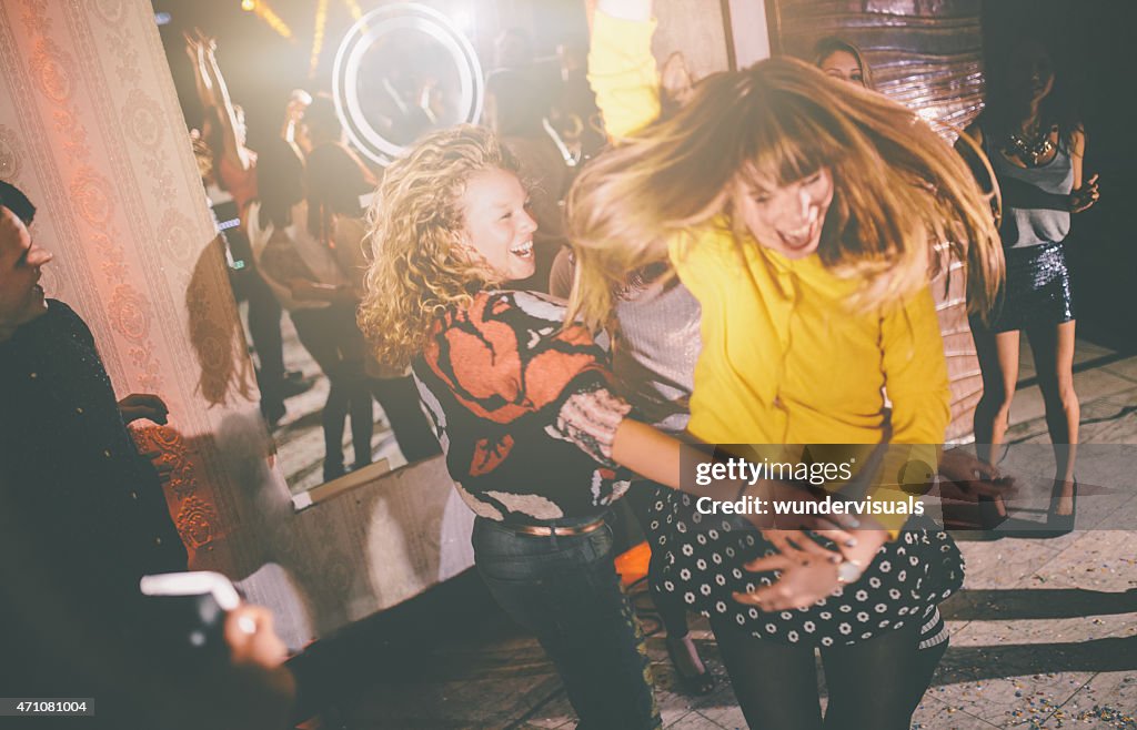 Crazy friends dancing wildly at a party in a club