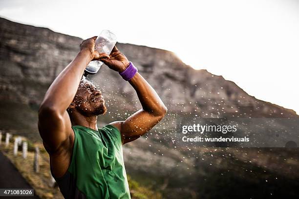 athlète éclabousser lui-même avec l'eau de sa bouteille d'eau - man drinking water photos et images de collection