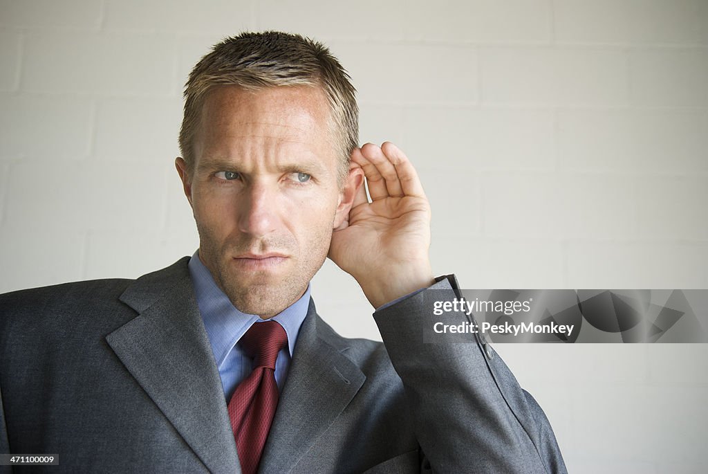 Gossip Businessman Cupping his Ear Listening to White Copy Space