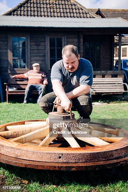 traditional wheelwright clamps a large wooden cartwheel, outside - colyton stock pictures, royalty-free photos & images