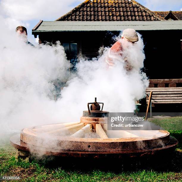 fitting the metal tyre onto a wooden cartwheel, traditional wheelwrights - colyton stockfoto's en -beelden