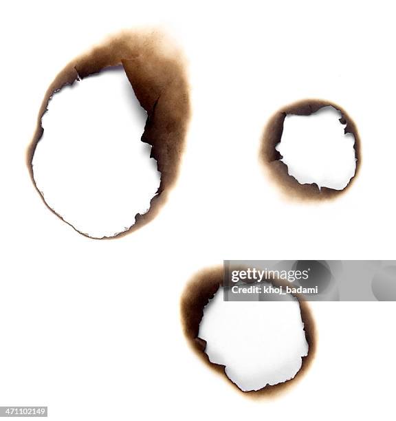 burnt holes in a piece of paper - burning stockfoto's en -beelden