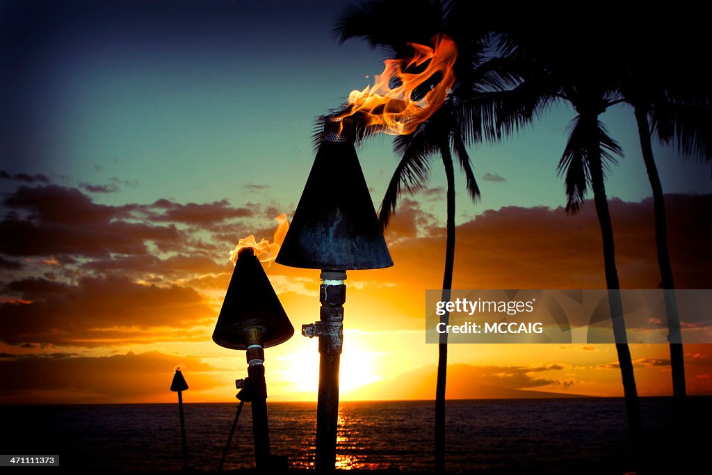Fire torches against a beautiful island sunset