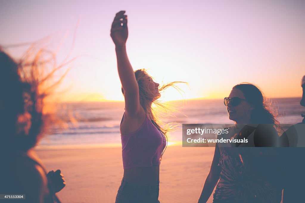 Ragazza sentirsi libero su una spiaggia al tramonto con gli amici