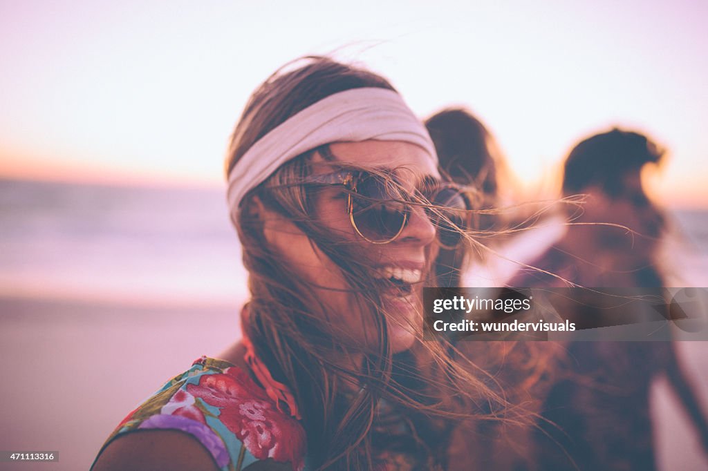 Boho Girl in sunglasses laughing on a beach with friends