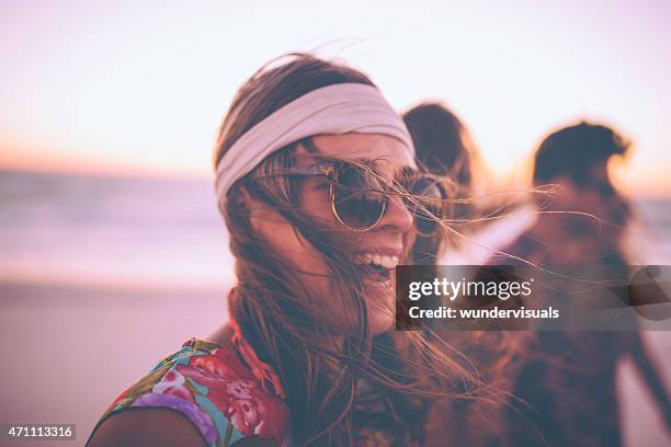 boho girl in sunglasses laughing on a beach with friends - human hair strand stock pictures, royalty-free photos & images