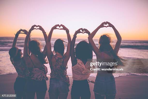 silhouette der mädchen machen herz formen mit ihren händen - girl beach sunset stock-fotos und bilder