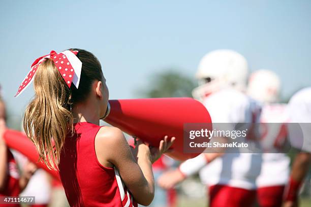 cheerleader with megaphone cheers for her football team - cheerleader photos stock pictures, royalty-free photos & images