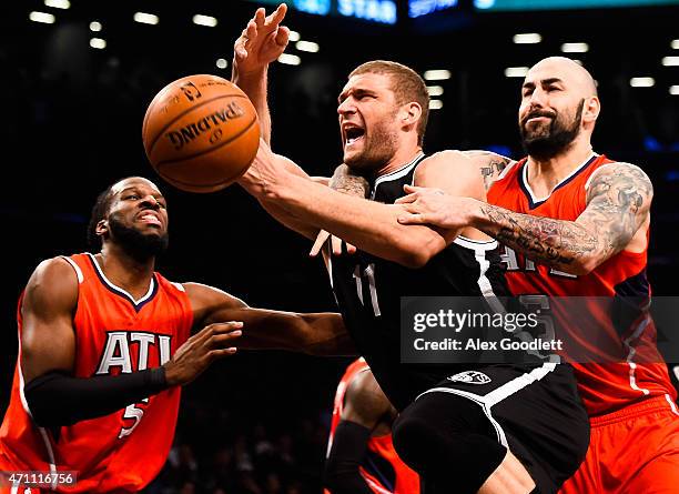 Brook Lopez of the Brooklyn Nets attempts to drive past Pero Antic and DeMarre Carroll of the Atlanta Hawks during the first round of the 2015 NBA...
