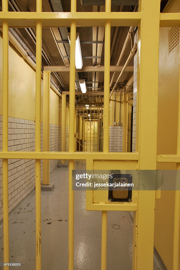 Prison corridor with yellow security gate in foreground