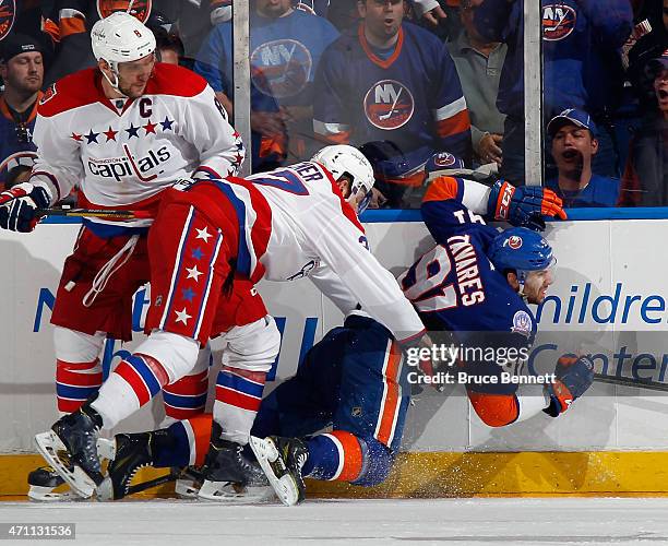 Karl Alzner of the Washington Capitals hits John Tavares of the New York Islanders into the boards during the third period in Game Six of the Eastern...