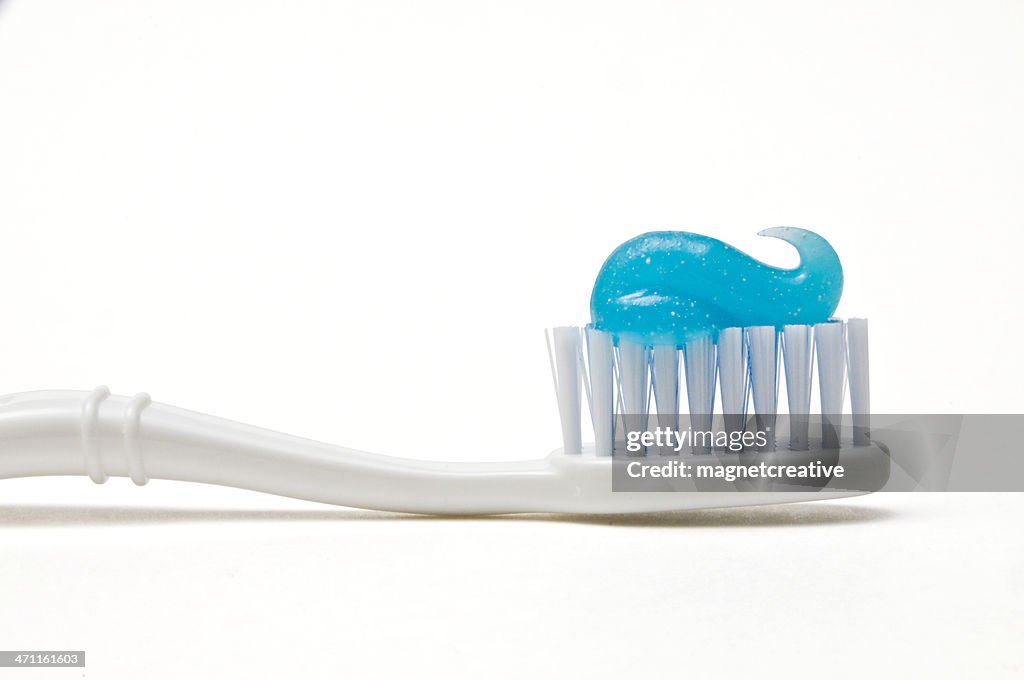 White toothbrush with blue swirl of toothpaste