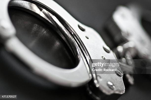 black and white close-up of silver handcuffs - under arrest stock pictures, royalty-free photos & images