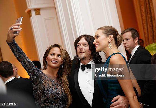 Model Chrissy Teigen, left, actor Norman Reedus, center, and model Hannah Davis pose for a "selfie" photograph while attending the Bloomberg Vanity...