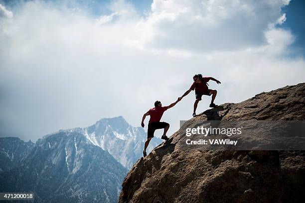 hikers ayudar - alpinismo fotografías e imágenes de stock