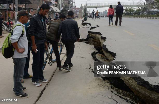 Nepalese residents walk past road damage following an earthquake in Kathmandu on April 26, 2015. International aid groups and governments intensified...