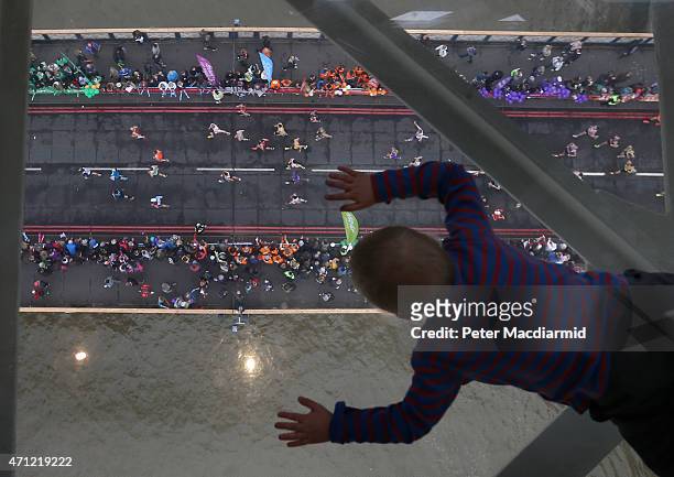 Young visitor to Tower Bridge's Exhibition glass walkway watches runners on The Virgin Money London Marathon cross the River Thames on April 26, 2015...