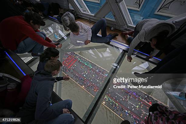 Visitors to Tower Bridge's Exhibition glass walkway watch runners on The Virgin Money London Marathon cross the River Thames on April 26, 2015 in...