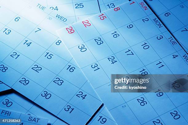 blue tinted image of calendars with light rays - calendar stockfoto's en -beelden