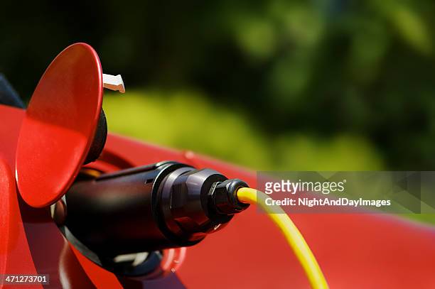 black plug of red electric car recharging - red car wire stock pictures, royalty-free photos & images