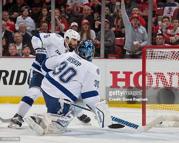 Jason Garrison and goalie Ben Bishop of the Tampa Bay Lightning reach back for a puck that scored on a flipping shot from Joakim Andersson of the...
