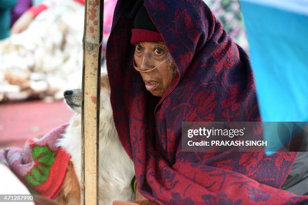 Nepalese patient Sanu Ranjitkar breathes oxygen from a cylinder under a makeshift shelter in Kathmandu on April 27 two days after a 7.8 magnitude...