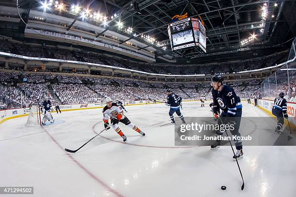 Adam Lowry of the Winnipeg Jets plays the puck as Jakob Silfverberg of the Anaheim Ducks defends during first-period action in Game Three of the...