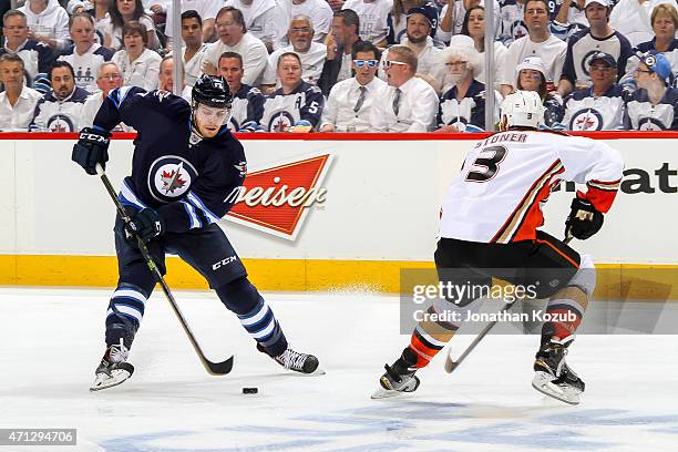 Adam Lowry of the Winnipeg Jets plays the puck around Clayton Stoner of the Anaheim Ducks during third-period action in Game Three of the Western...