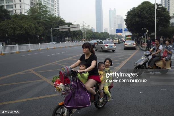 In a picture taken on April 24 a woman rides her scooter with three children along a road in the southern Chinese city of Shenzhen. AFP PHOTO / FRED...