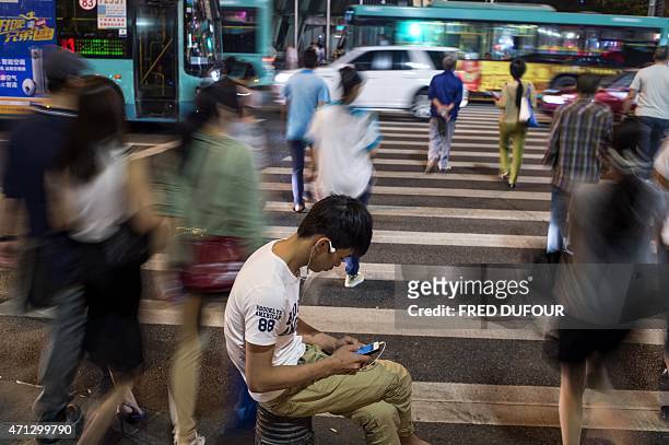 In a picture taken on April 24 a man makes a phone call on a street in the southern Chinese city of Shenzhen. AFP PHOTO / FRED DUFOUR