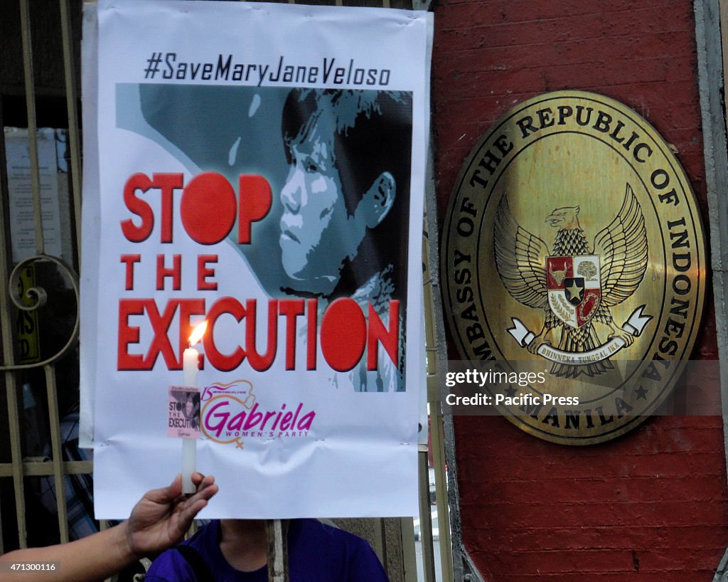 A Filipino activist holds a lighted candle beside a placard...