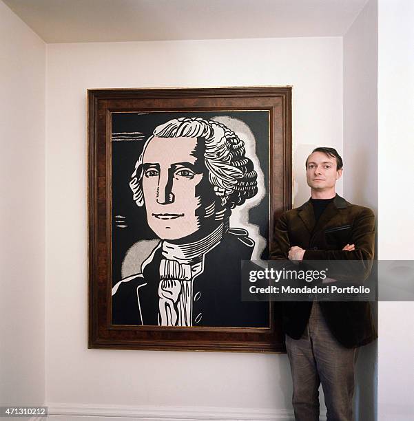 The American painter and representatvie of Pop Art, Roy Lichtenstein poses seriously with his arms folded and close to one of his pictures. 1964.