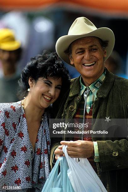 Laughters and jokes between Pugliese show man Renzo Arbore, who brings two shopping bags, and Neapolitan actress Marisa Laurito; the two artists are...