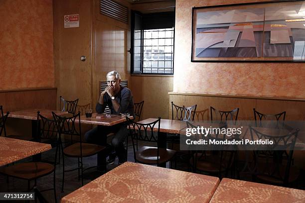 Teo Teocoli seats at a table in a coffee shop waiting for some friends to play cards with; the Italian comic actor started his career as a cabaret...