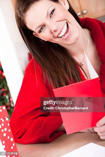 smiling woman reading christmas card - receiving card stock pictures, royalty-free photos & images
