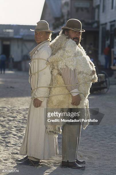 Italian actor and director Terence Hill and Italian actor Bud Spencer standing tied together by a rope on the set of the film Troublemakers. Santa...