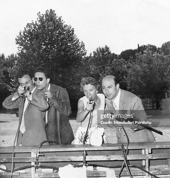 Quartetto Cetra pointing some toy guns at the fun fair. The Italian vocal band is formed by the singer Lucia Mannucci, the singer and drummer Felice...