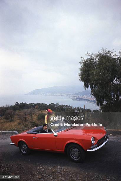 Young people travelling on a Fiat 124 Spider. 1960s