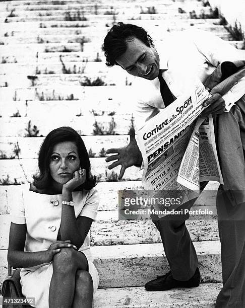 Man reading the Corriere dello Sport and bothering his girlfriend. Italy, 1960s