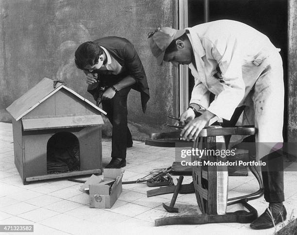 Two Italian university students fixing a chair and a dog basket. The students are members of the Gruppo Universitario Assistenza. Rome, 1964