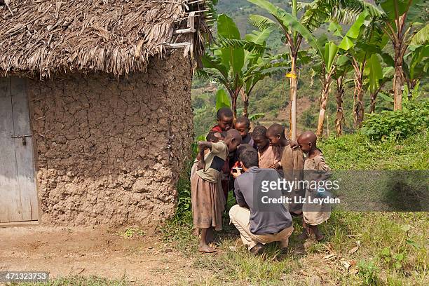 young tourist showing ugandan children photos on digicam - liz white stock pictures, royalty-free photos & images