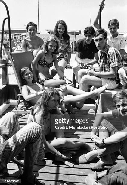Some boys and girls smiling on a dock. Forte dei Marmi, August 1966