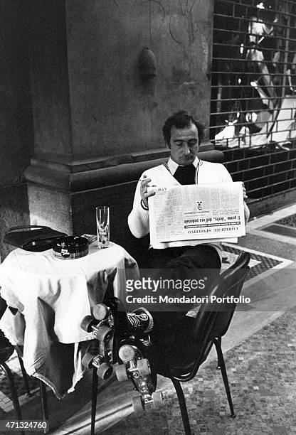 Man in roller skates reading the Corriere Sportivo in a cafe on the first Italian walking Sunday due to the oil crisis, Milan, 2nd December 1973.
