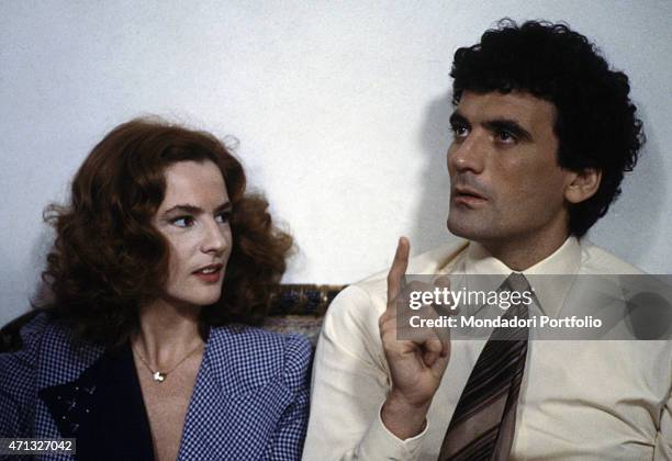 Italian actor and director Massimo Troisi gesticulating beside Italian actress Giuliana De Sio on the set of the film Scusate il ritardo. 1983