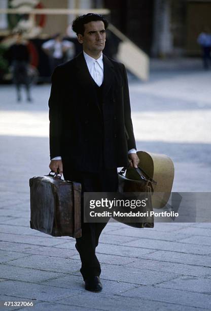 Italian actor and director Massimo Troisi holding some suitcases in the film Le vie del Signore sono finite. 1987