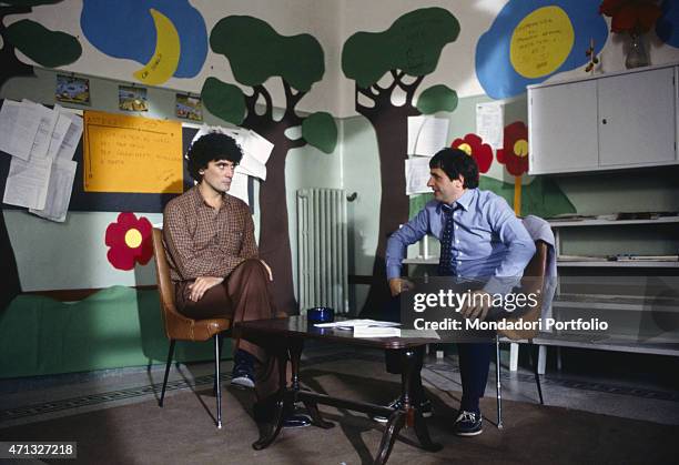 Italian actors and directors Massimo Troisi and Marco Messeri sitting in a classroom in the film I'm Starting from Three. 1981