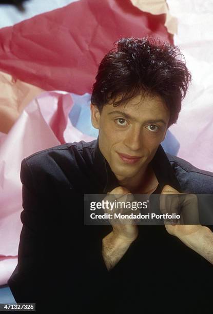 Italian singer-songwriter Raf posing lifting the collar of his black jacket. Italy, 1984